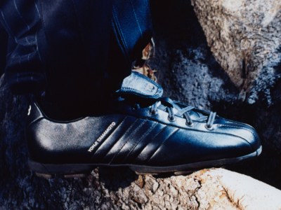 A close-up view of a person's foot wearing a black and blue athletic shoe, standing on a rocky, textured surface.