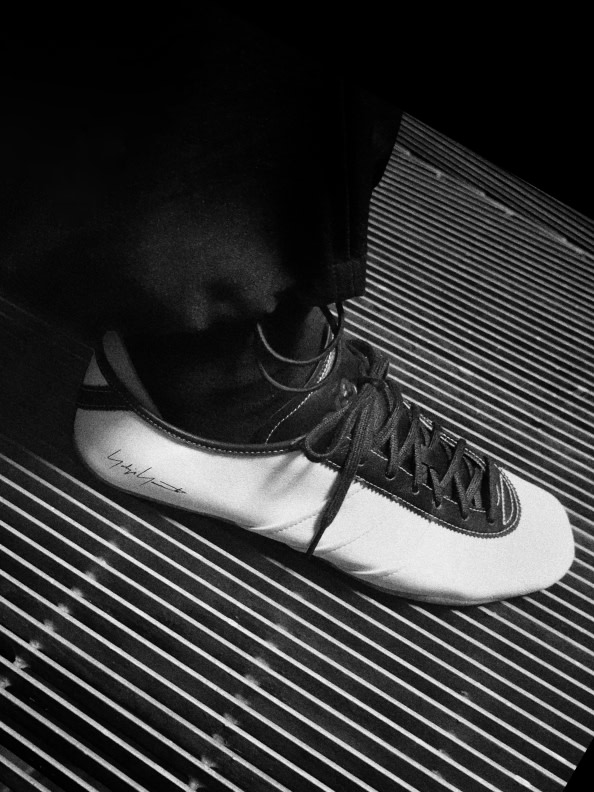 A black-and-white image of a sneaker resting on a surface with parallel lines, creating a striking visual contrast.