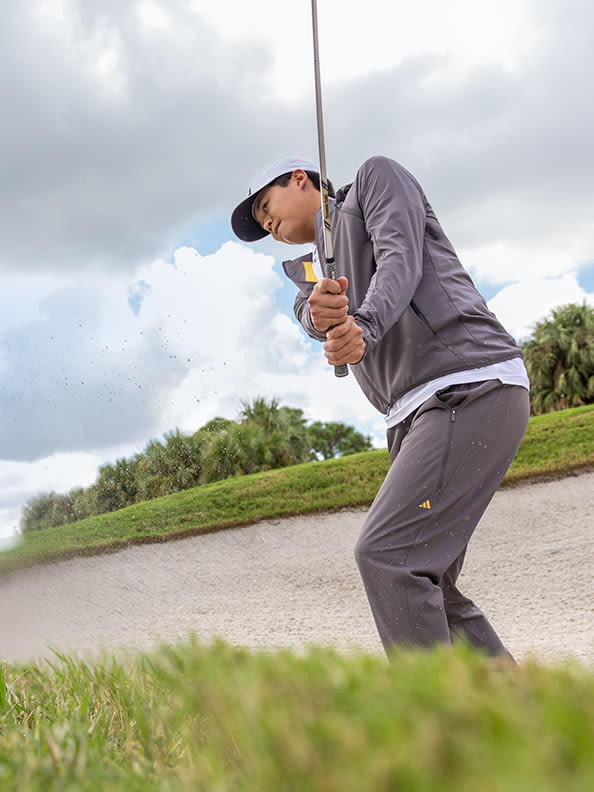 Man hitting golf ball from sand