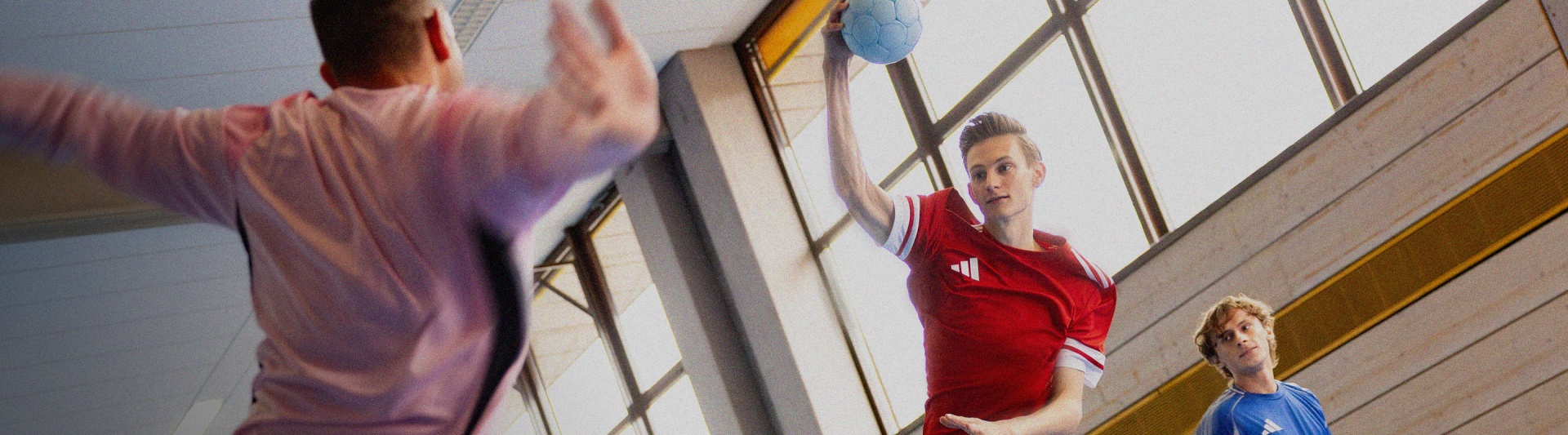 A person in a red jacket stands in a hallway with colorful abstract art on the walls.