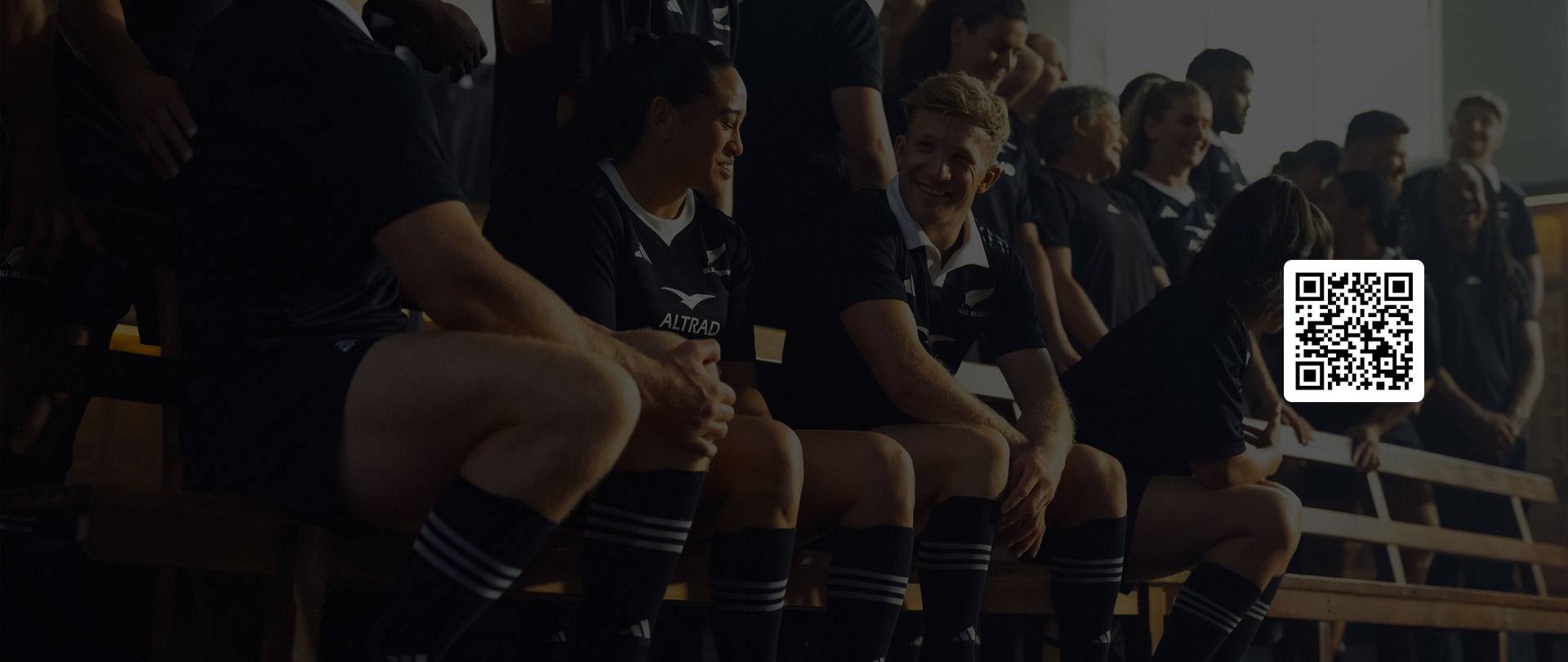 A group of people, likely athletes, wearing dark uniforms and standing in a row, with the background appearing to be a dimly lit indoor setting.