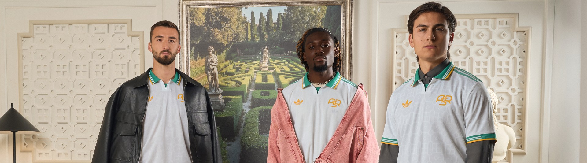 Tre persone che indossano maglie sportive sono in primo piano, con un lussureggiante paesaggio giardino visibile sullo sfondo.