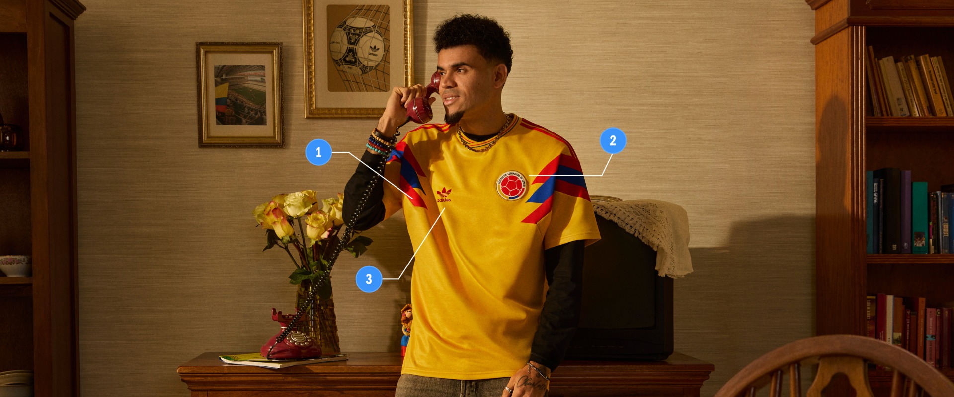 The image shows a person wearing a yellow soccer jersey standing in a room with framed artwork and a vase of flowers on a wooden table.