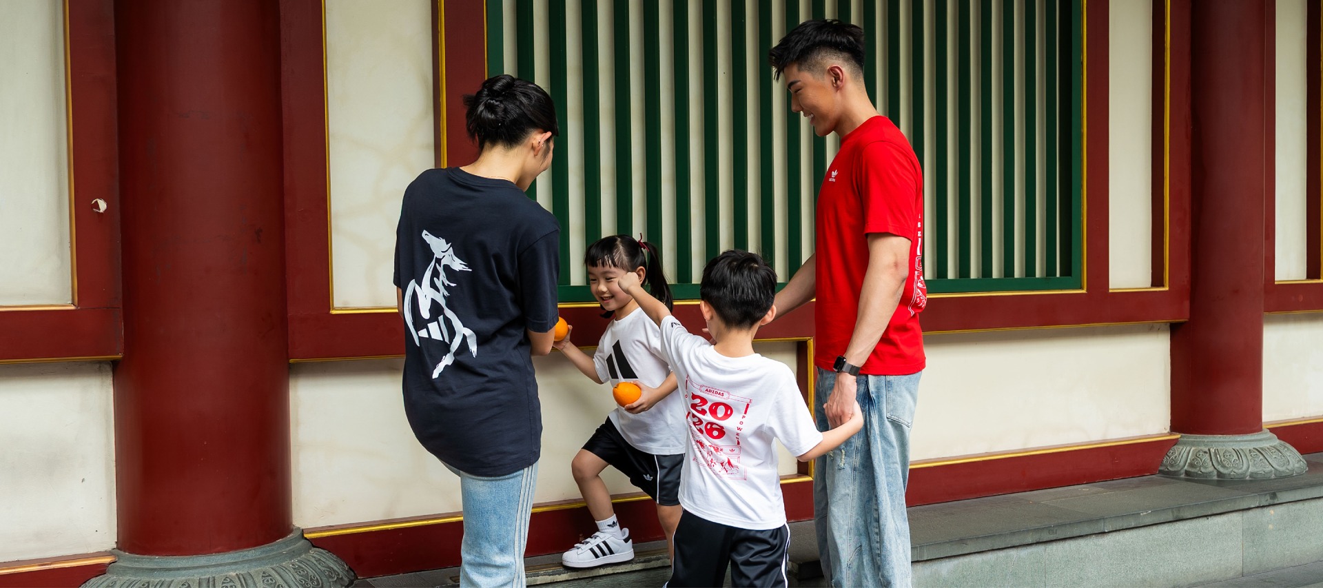 The image shows a group of young people standing in front of a traditional Japanese-style building, with one person wearing a red shirt and the others wearing various casual outfits.