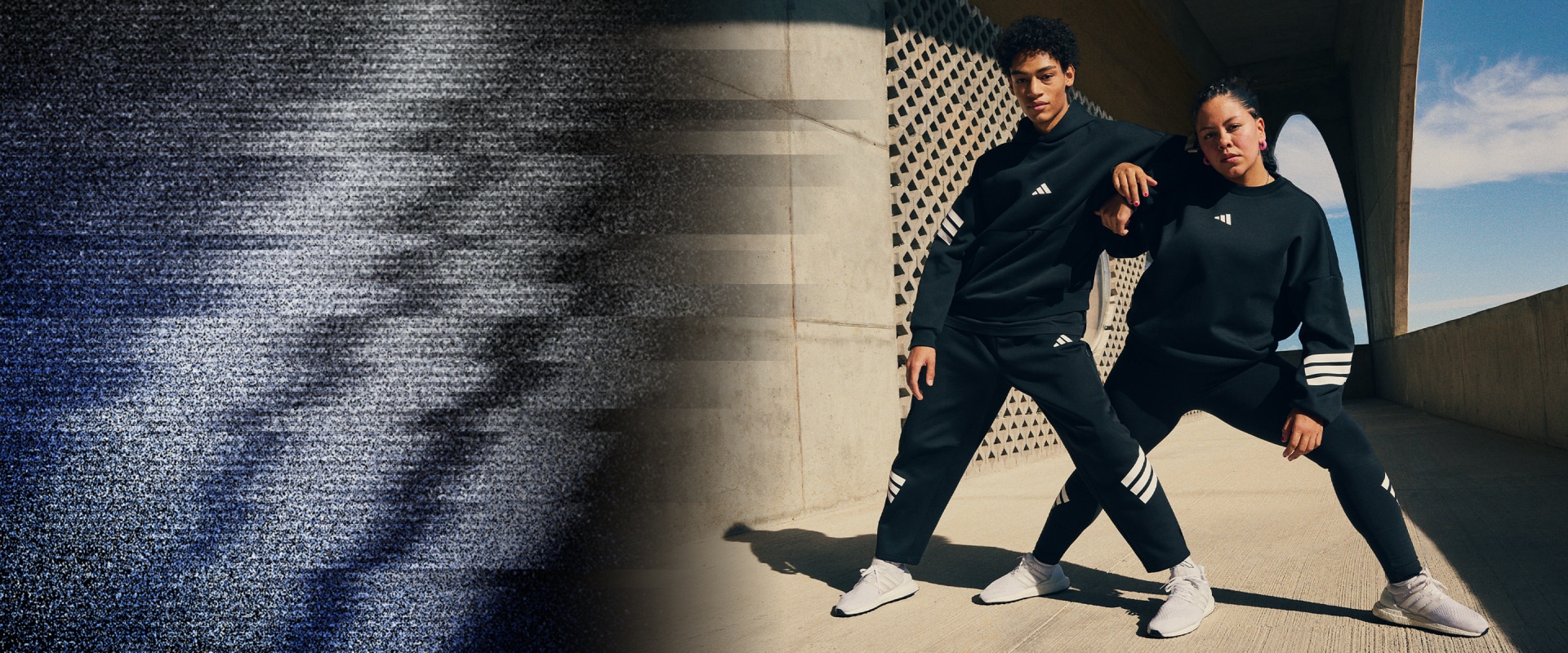 Dvaja ľudia v čiernom športovom oblečení stoja v slabo osvetlenej chodbe so vzorovanou stenou v pozadí.