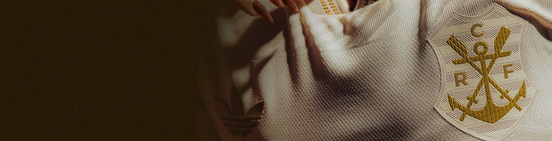 The image shows a close-up view of a person's hands holding a piece of fabric, with a blurred background suggesting a textile or clothing-related setting.