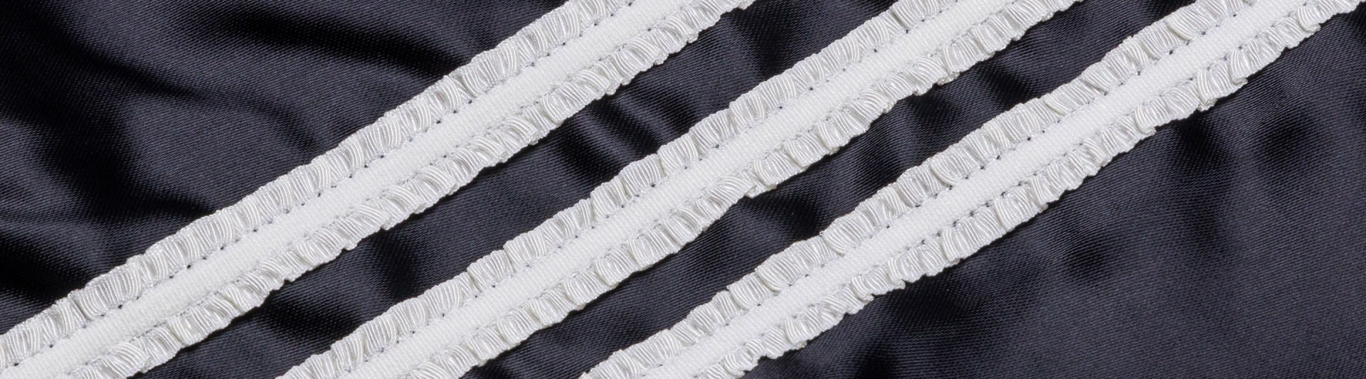 The image depicts a close-up view of a black and white striped fabric, with diagonal lines of white fringe running across the surface.