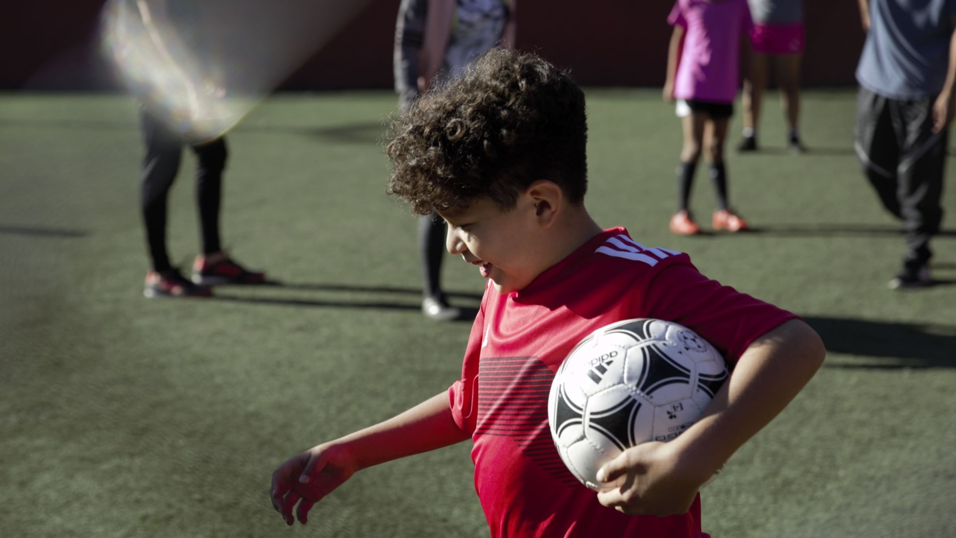 A young boy with a football under his arm