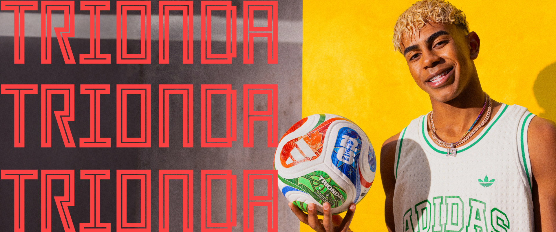 A smiling individual wearing an Adidas jersey stands in front of a vibrant red and black background.