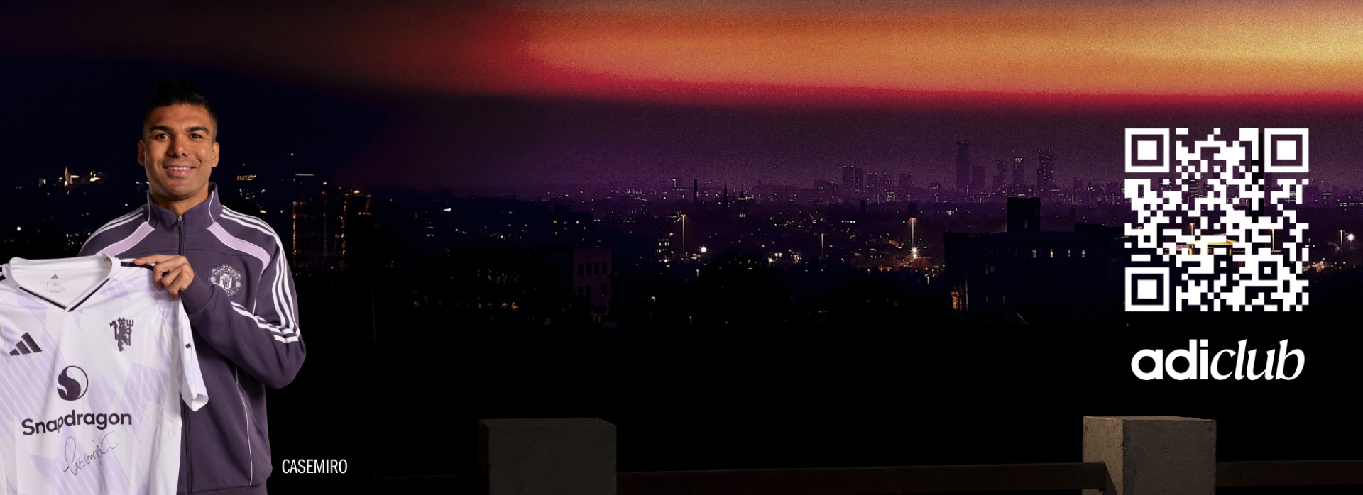 The image shows a person wearing a white shirt standing in the foreground, with a cityscape visible in the background against a vibrant sunset sky.