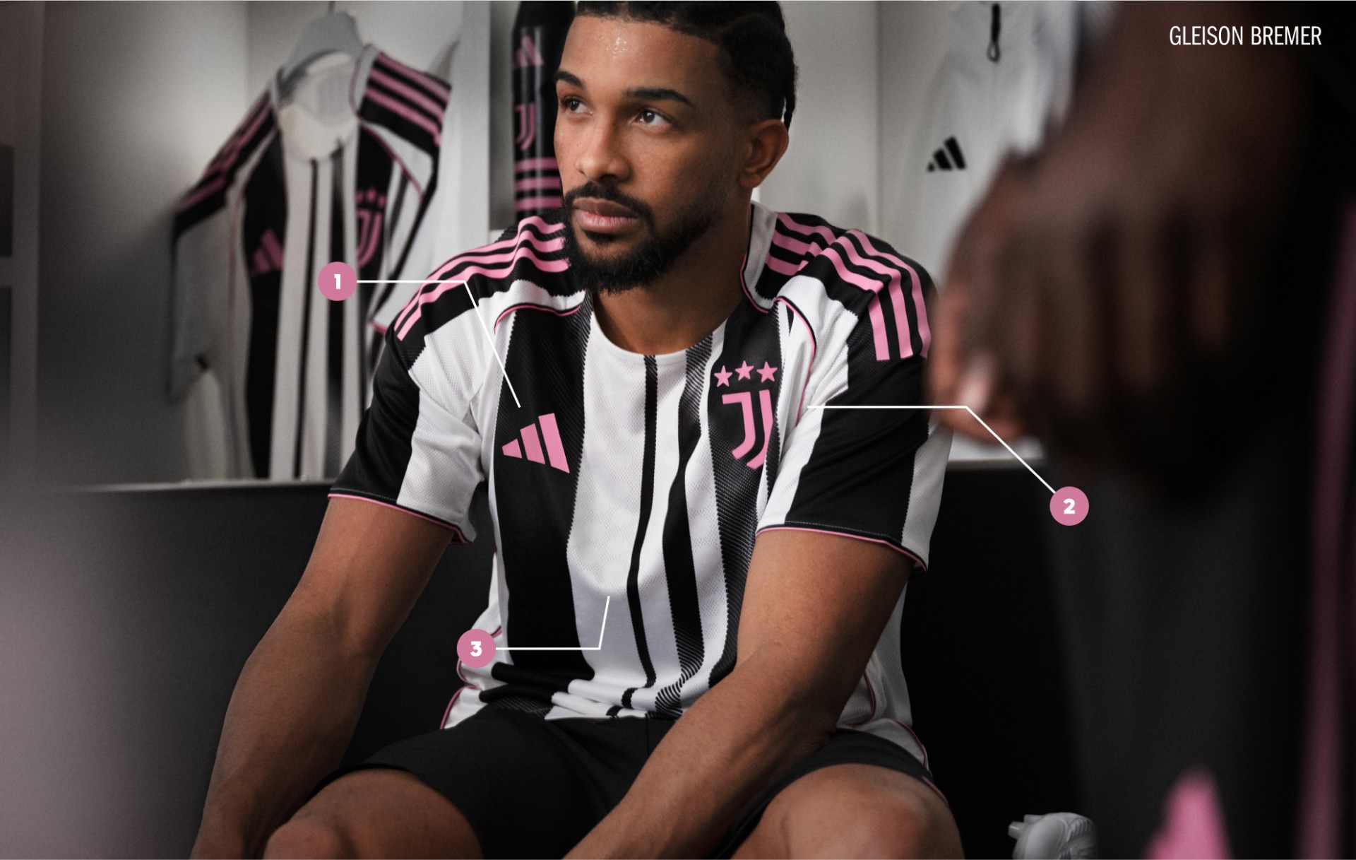 A man wearing a striped jersey and shorts is sitting in a dimly lit room, with a wall in the background.