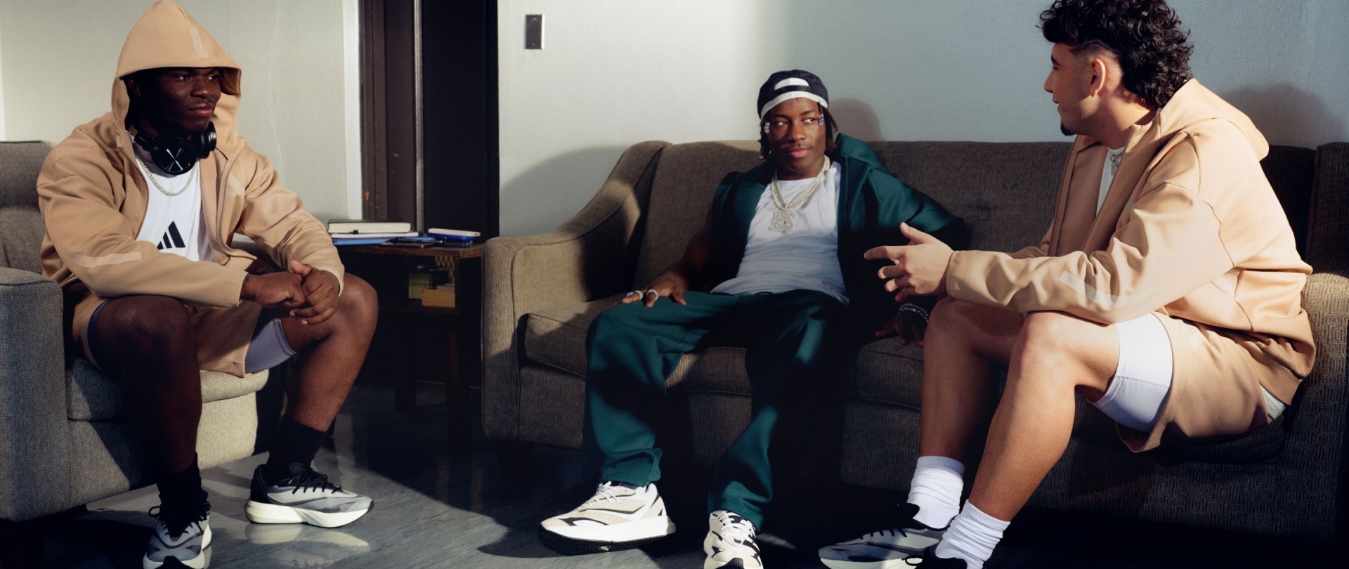 Three young men sit around on sofas wearing apparel from the new ADIDAS Z.N.E. range.