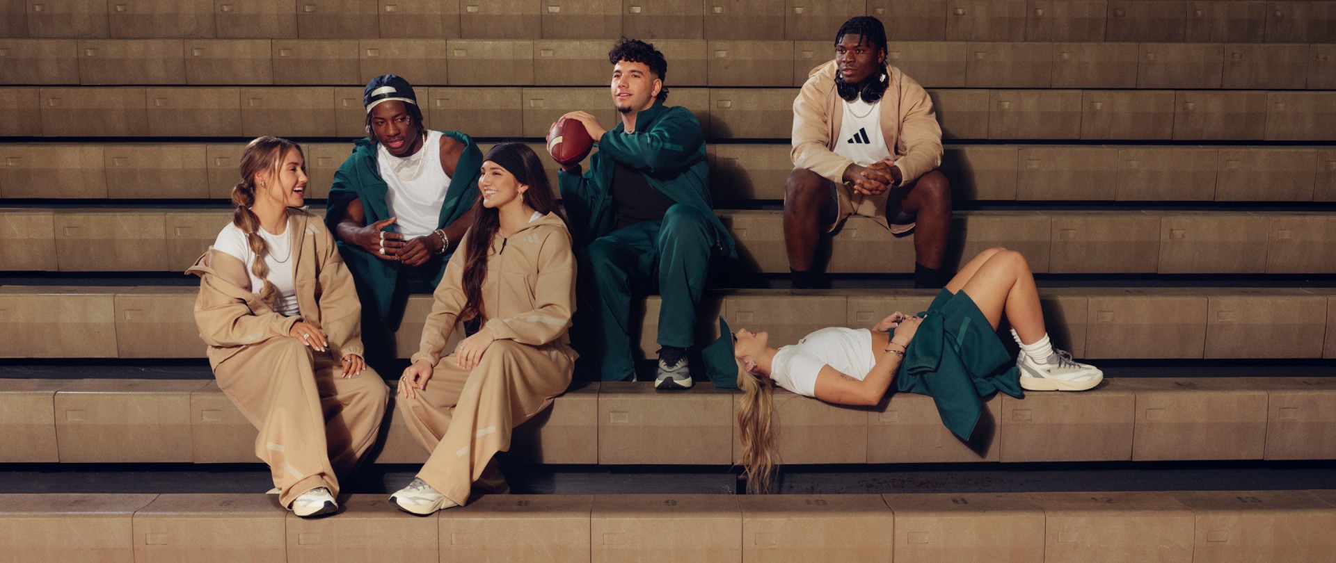 A group of young people sit on the steps of an indoor gym, wearing apparel from the new ADIDAS Z.N.E. range.