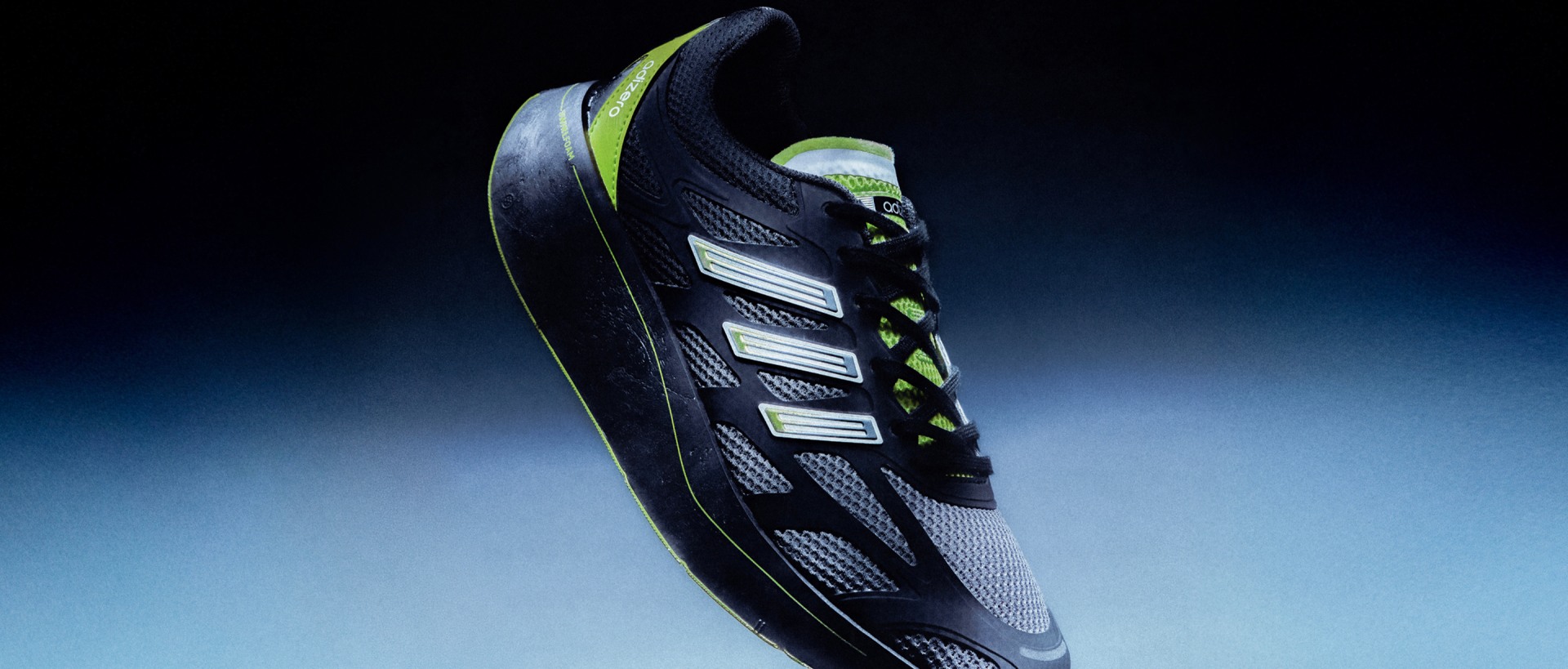 A sleek, black and green athletic shoe with distinctive stripes and a dark background.
