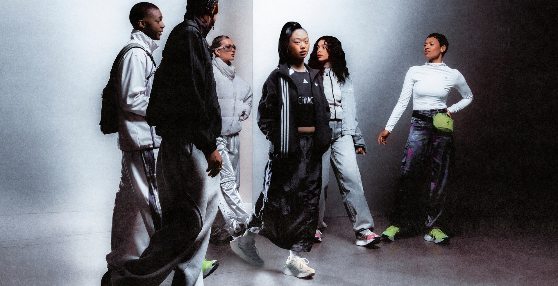 A group of individuals wearing stylish, avant-garde fashion pieces, standing against a plain, light-colored background.