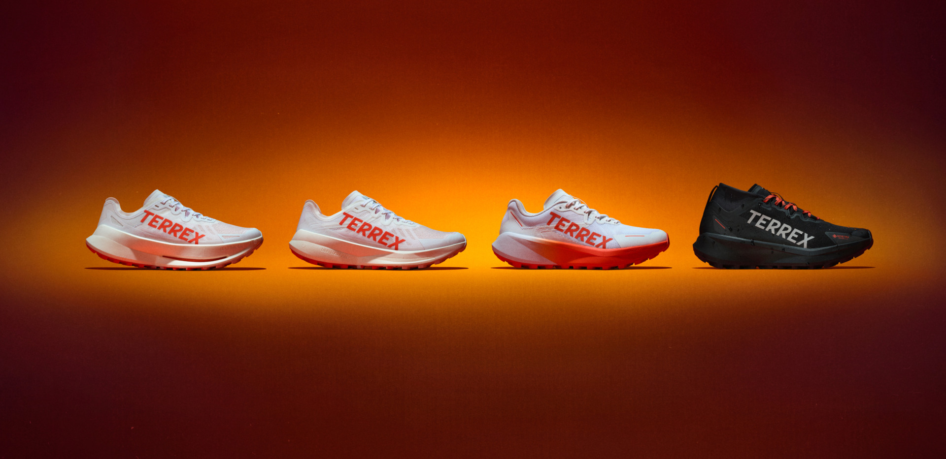 Four different adidas Agravic trail running shoes in a row, against an orange backdrop.