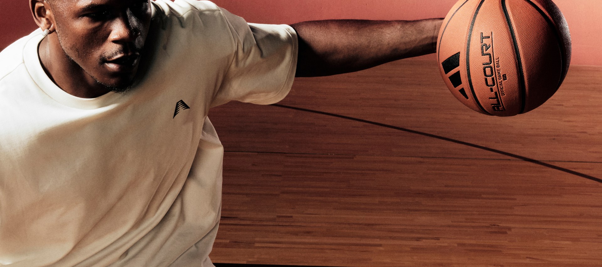 Anthony Edwards dribbles a basketball indoors while wearing a white adidas t-shirt.