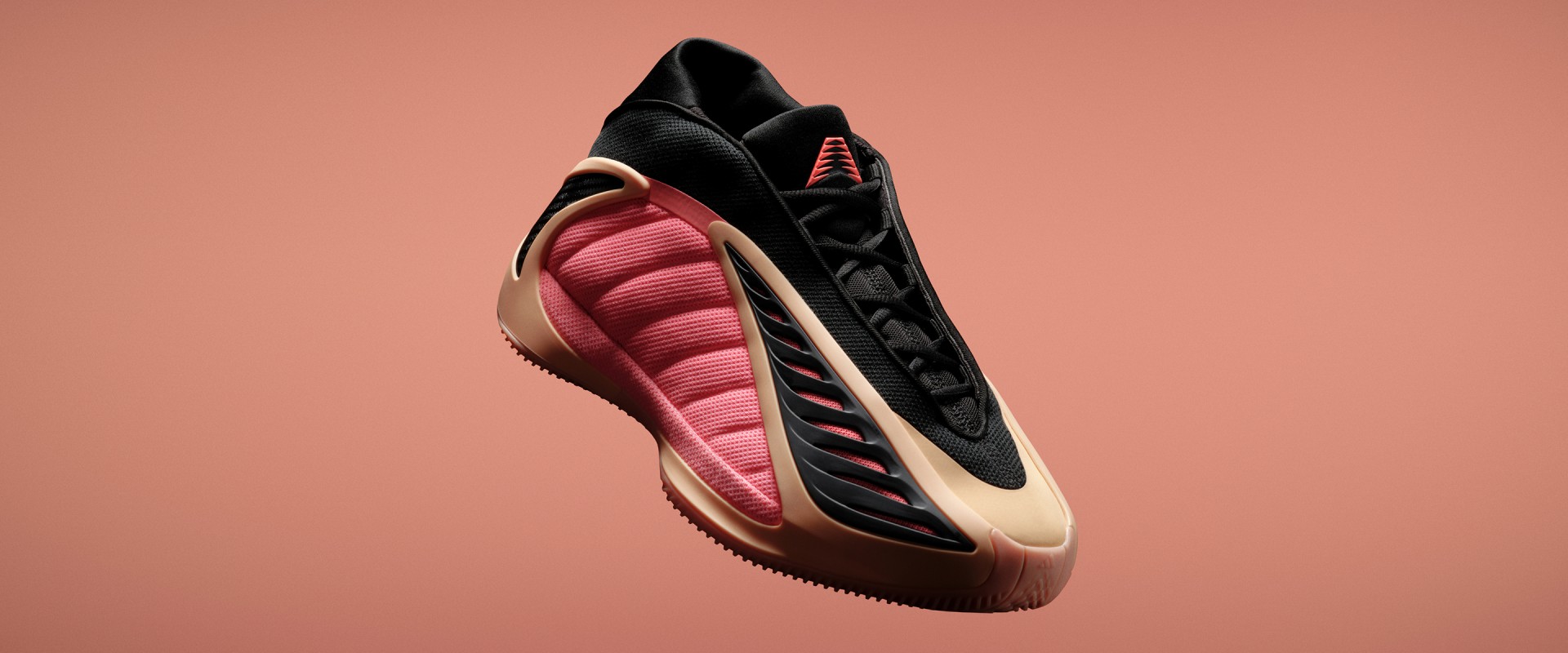 Close-up of the adidas Anthony Edwards 2 basketball sneaker in black, red, and beige on an orange background.