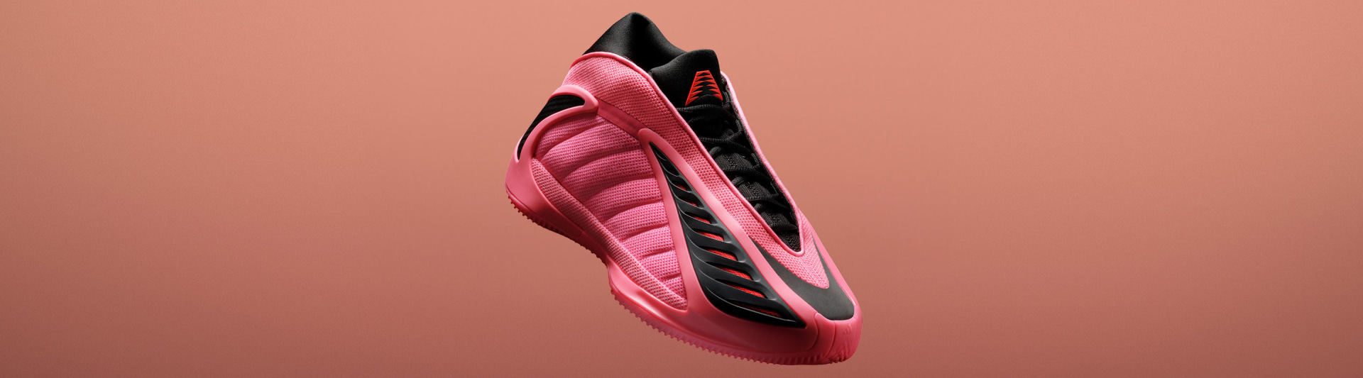 A pink and black adidas Anthony Edwards 2 basketball sneaker shown angled against a orange background. It has a sculpted sole and wave-like side design.