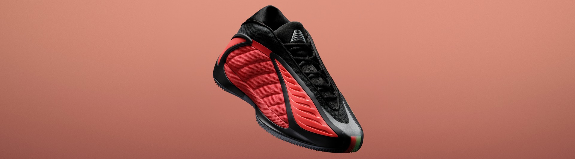 Las zapatillas de básquet adidas Anthony Edwards 2 en rojo y negro sobre un fondo naranja. Luce una suela esculpida y un diseño lateral ondulado. 