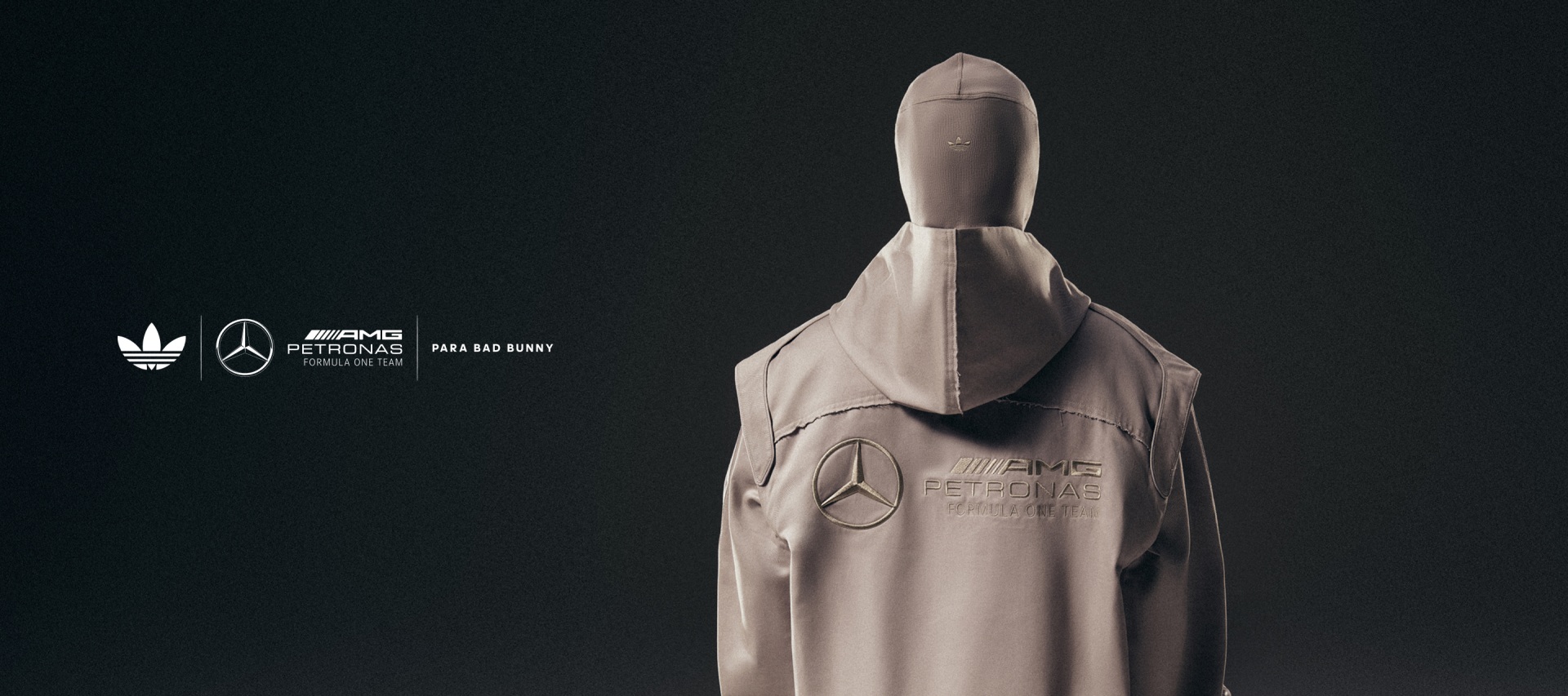 Una persona con guantes amarillos sostiene unos tenis adidas Adiracer GT negros con rayas blancas y el logo amarillo de la colección adidas para Bad Bunny x Mercedes-AMG PETRONAS F1 Team en el costado.