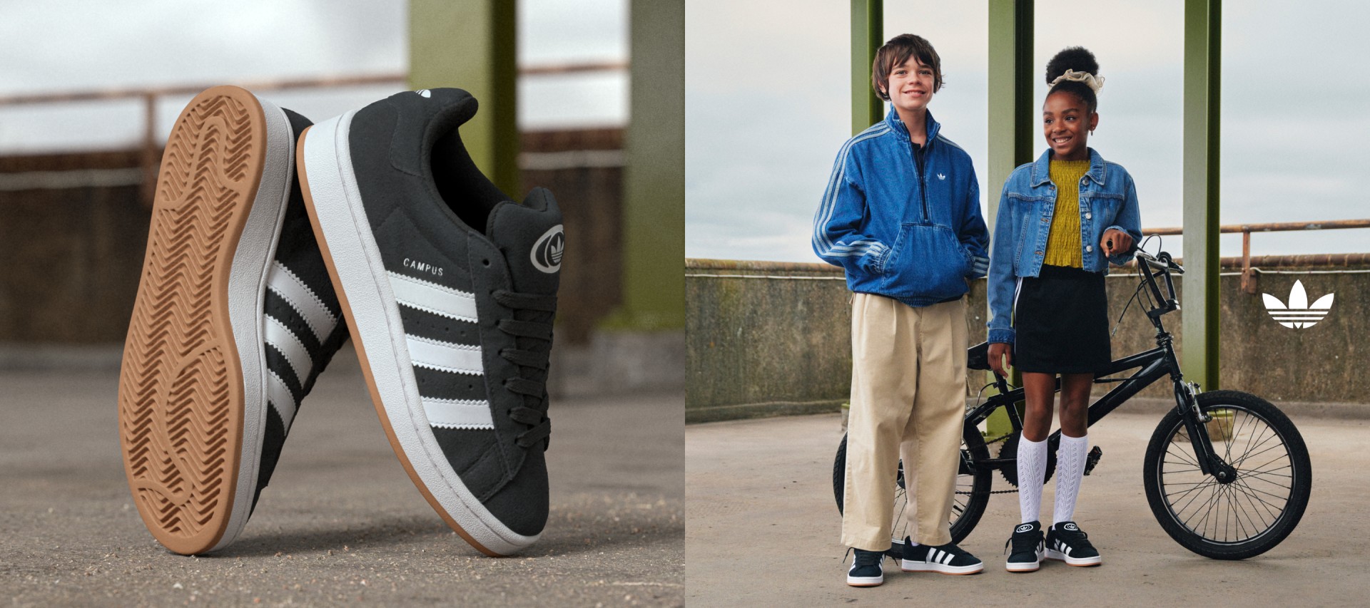 A girl and a boy smile as they pose next to a black bike on the streets, both wearing adidas apparel and black Campus 00s shoes.