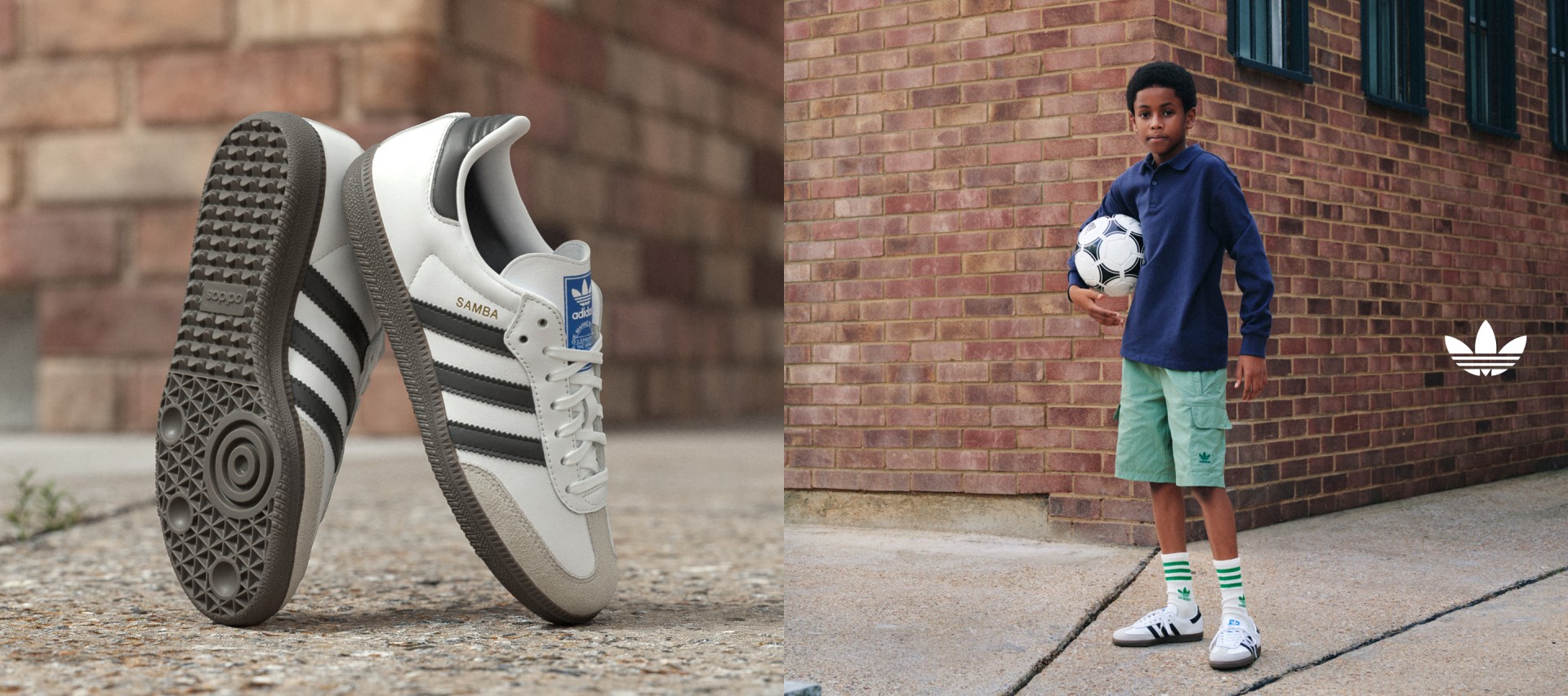 A boy in an adidas hoodie, green shorts, and white adidas Samba shoes stands in front of a brick wall with a soccer ball under one arm.