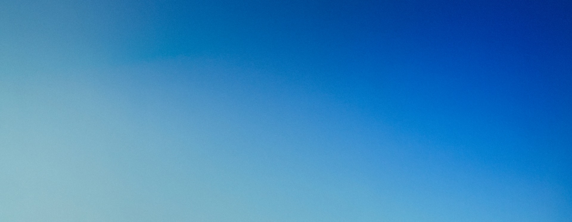 A pair of adidas Jude Bellingham Predator boots rest on a black bench, set against a cool blue gradient background.