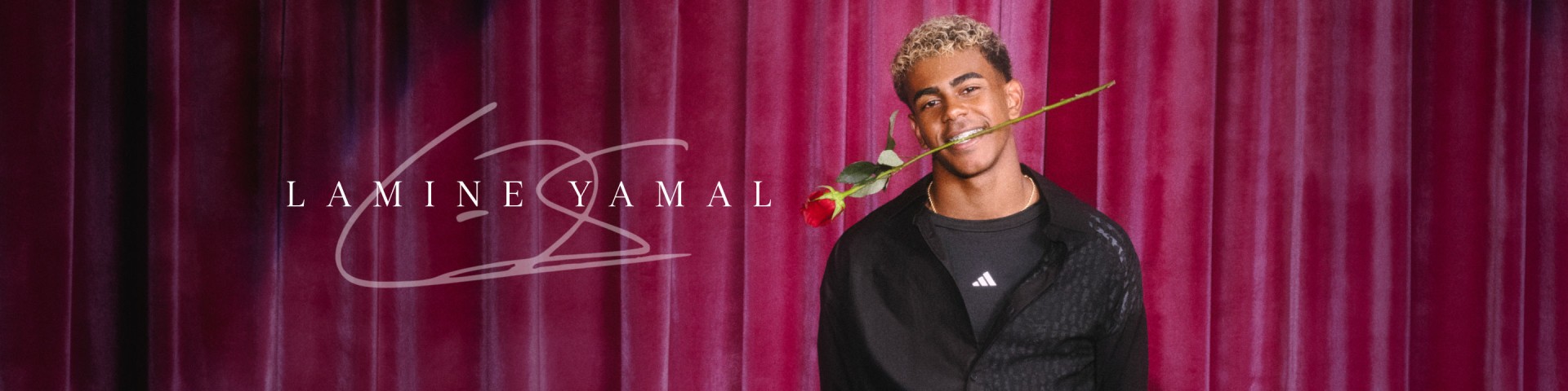 Lamine Yamal poses in a black adidas track top and tee, holding a red rose between his teeth with a playful smile.