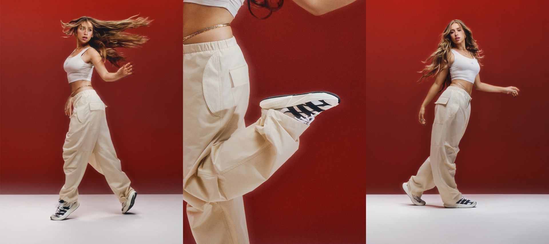 The image features a woman wearing a white outfit, including a cropped top and loose, flowing pants, posing against a vibrant red background. Her hair is tousled, and she appears to be in motion, conveying a sense of energy and dynamism.