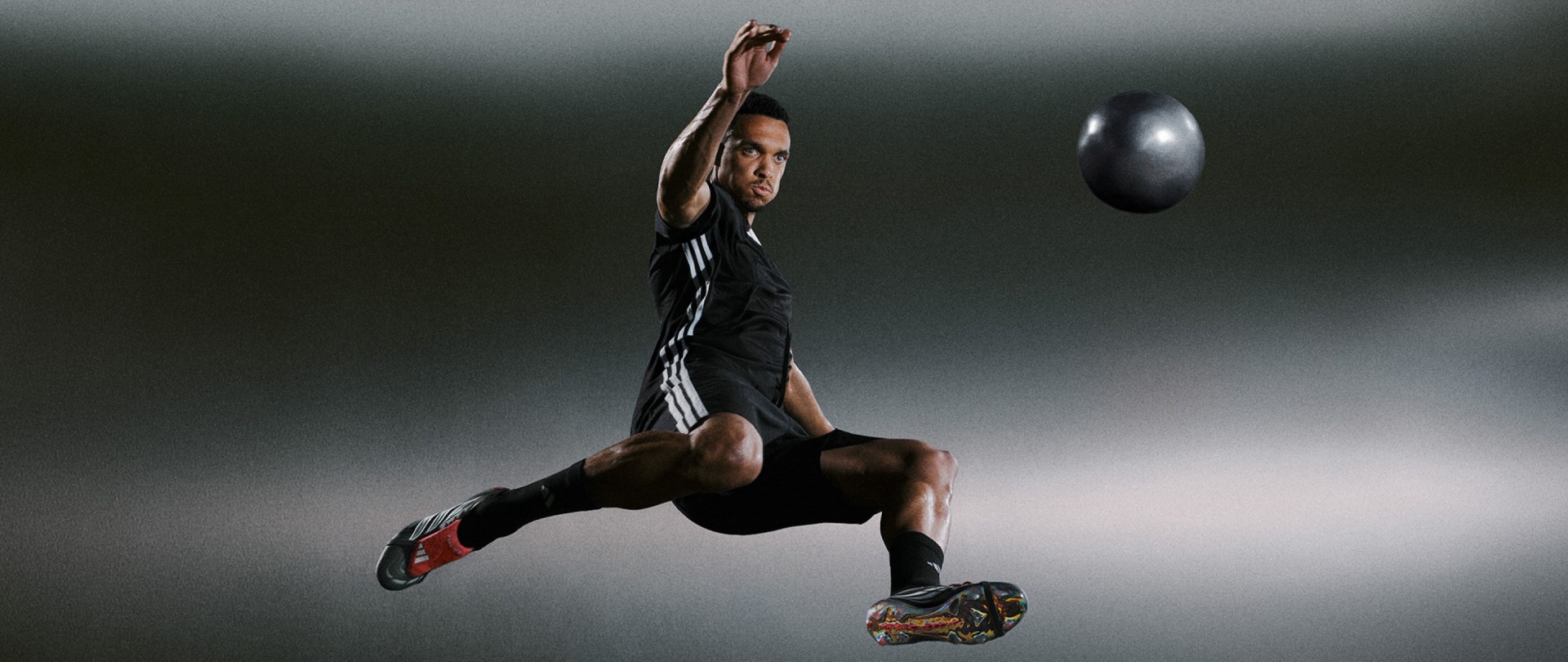 A muscular athlete in black athletic wear leaps through the air, reaching up with one arm while a rugby ball hovers in the background against a dark, moody backdrop.