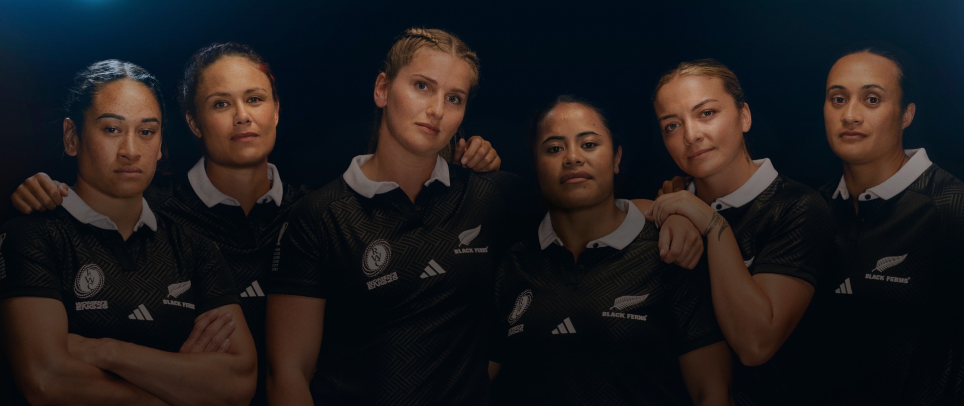 A group of young people wearing rugby uniforms, their faces illuminated against a dark background, creating an intense and dramatic atmosphere.