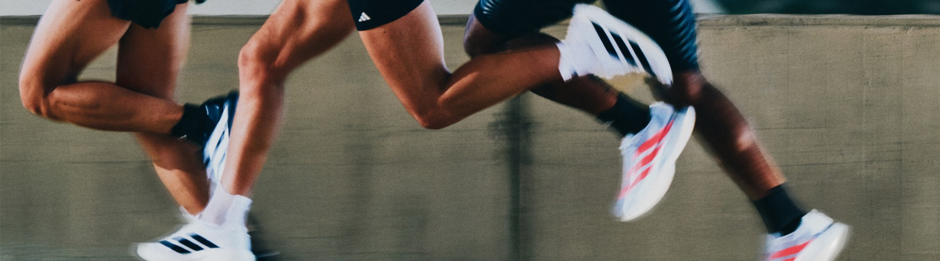 The image shows the lower body of two people engaged in what appears to be a sports activity, with their legs and feet visible in the foreground against a blurred background.