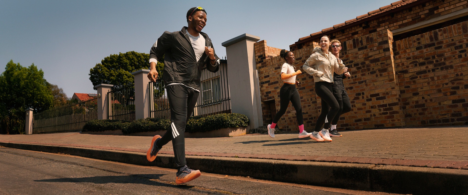 ภาพแสดงกลุ่มหนุ่มสาวยืนอยู่บนทางอิฐในบรรยากาศกลางแจ้ง มีอาคารและต้นไม้เขียวชอุ่มที่มองเห็นได้ในพื้นหลัง