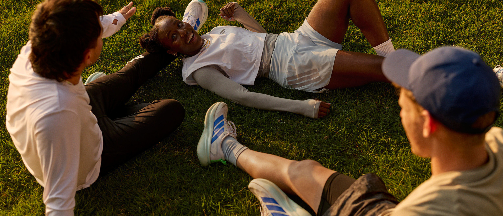 ภาพแสดงคนนอนอยู่บนสนามหญ้าล้อมรอบด้วยคนอื่น ๆ ในสนามที่มีพื้นหลังสีเขียวเข้ม