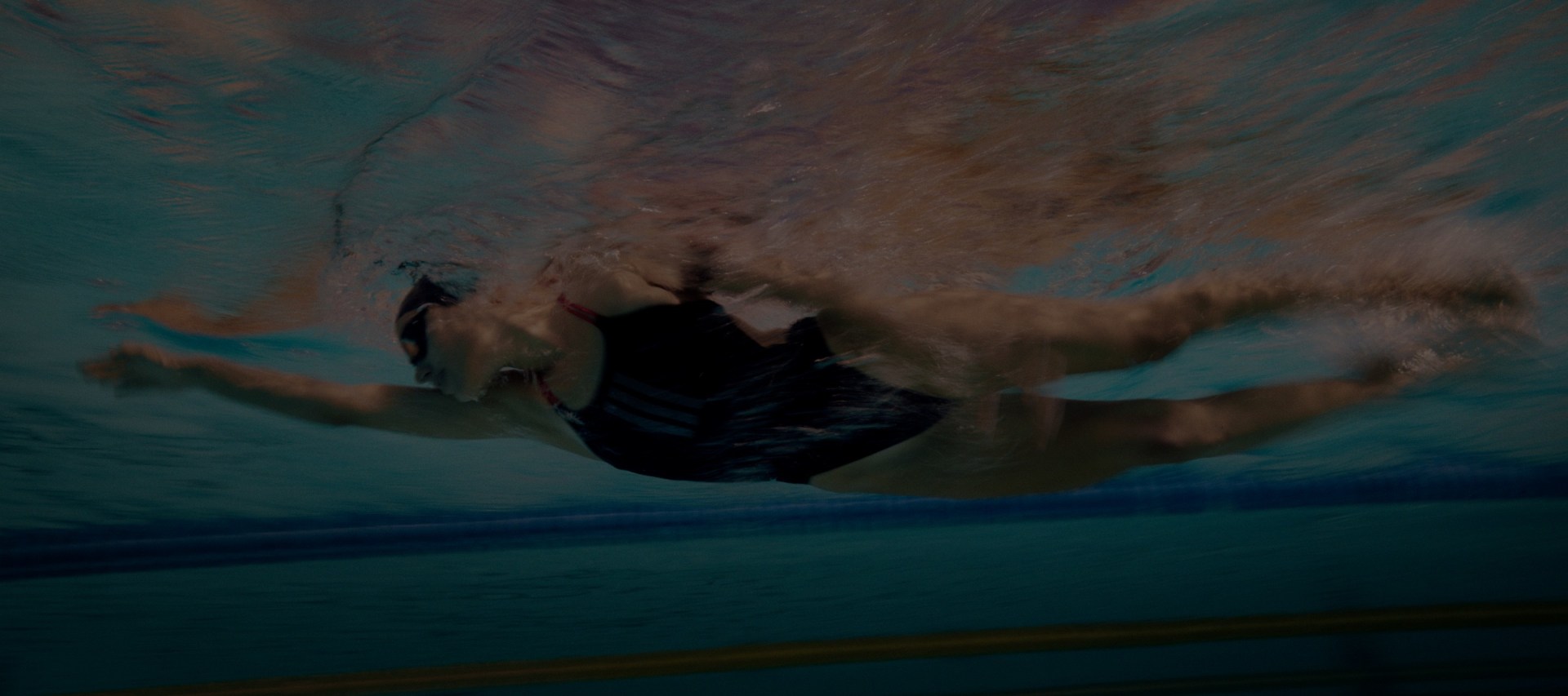 A woman standing by the sea wearing a multicolor adidas Originals bikini. and a close up of a man adidas originals swim shorts.
