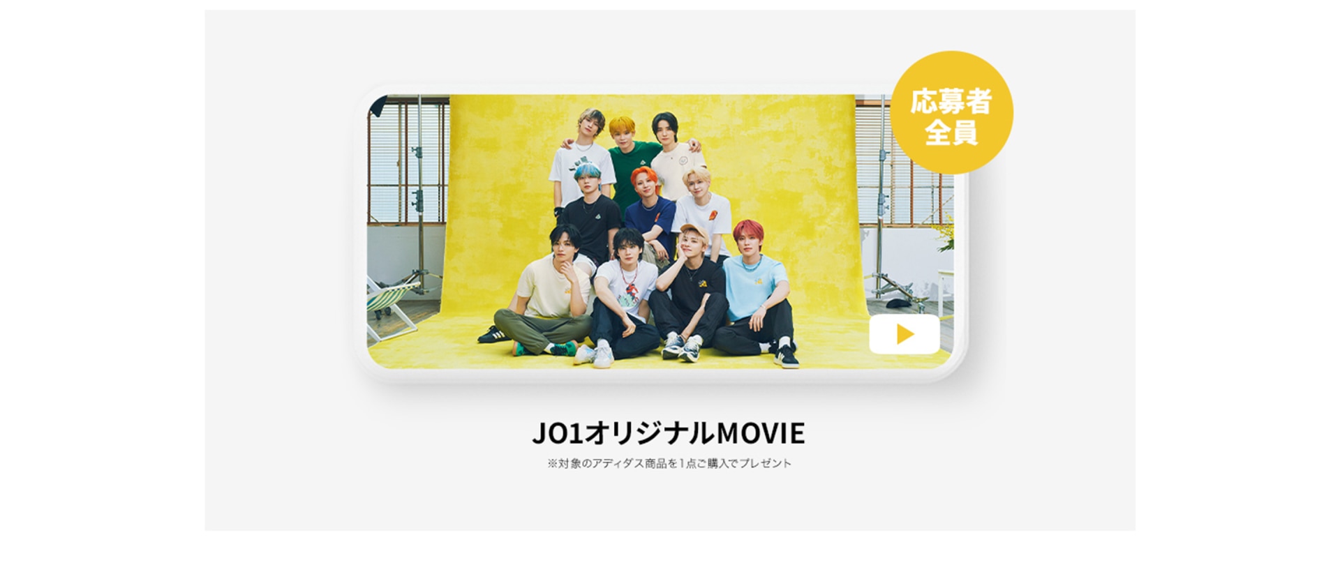 The image shows a group of people, likely the cast of a Japanese movie or television show, posing together on a yellow background.