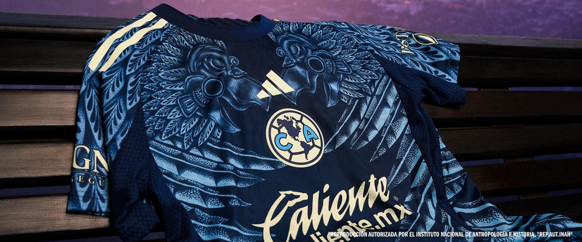 The image depicts a black and white patterned fabric or clothing item, possibly a jersey or shirt, with intricate designs featuring winged figures and a prominent logo or emblem.