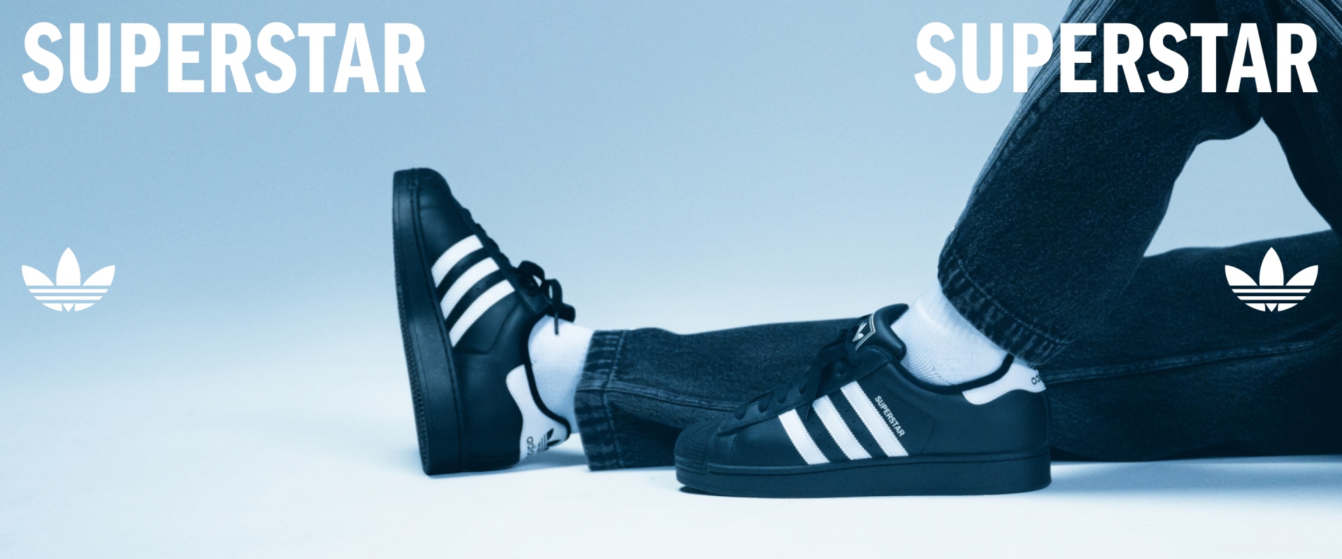 The image shows a pair of black and white sneakers with the Adidas logo prominently displayed, set against a blue sky background.