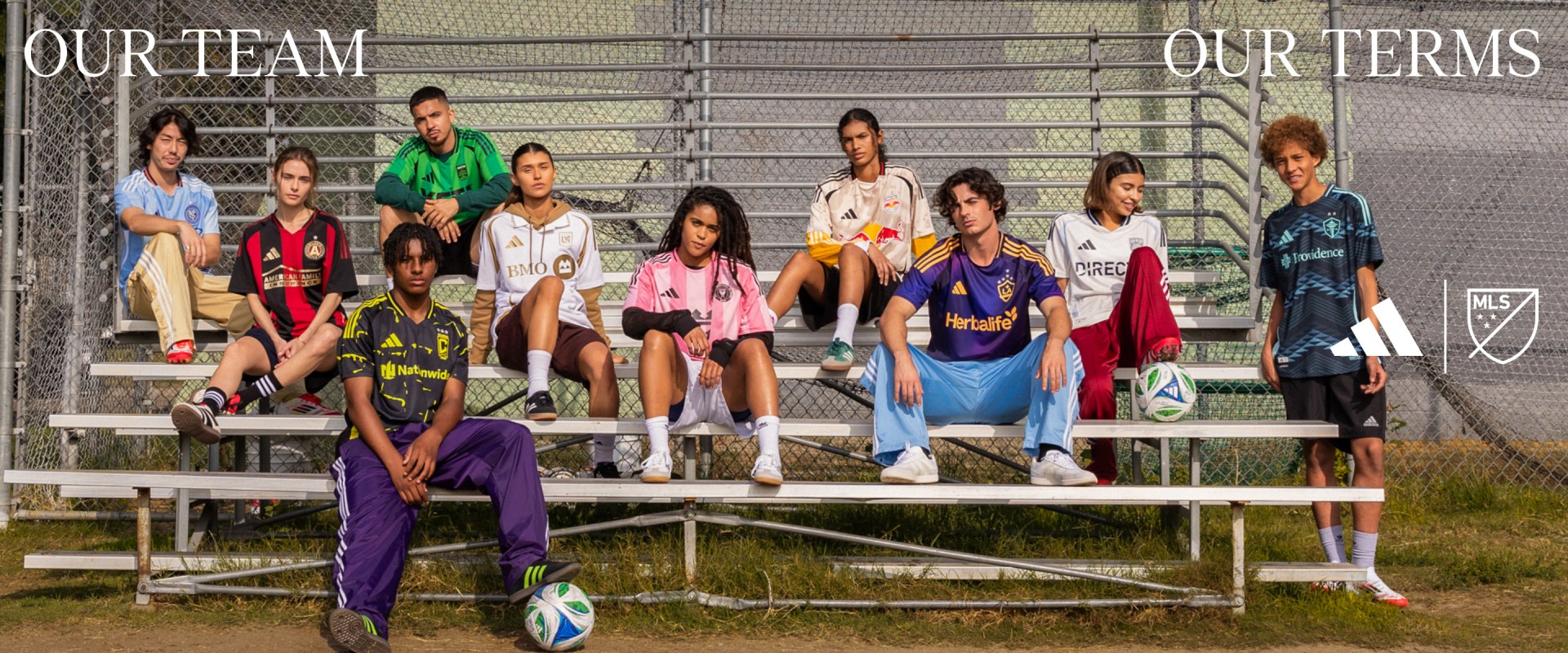 A group of diverse individuals, both male and female, are seated on bleachers, wearing various colorful sports jerseys and posing for a team photograph.
