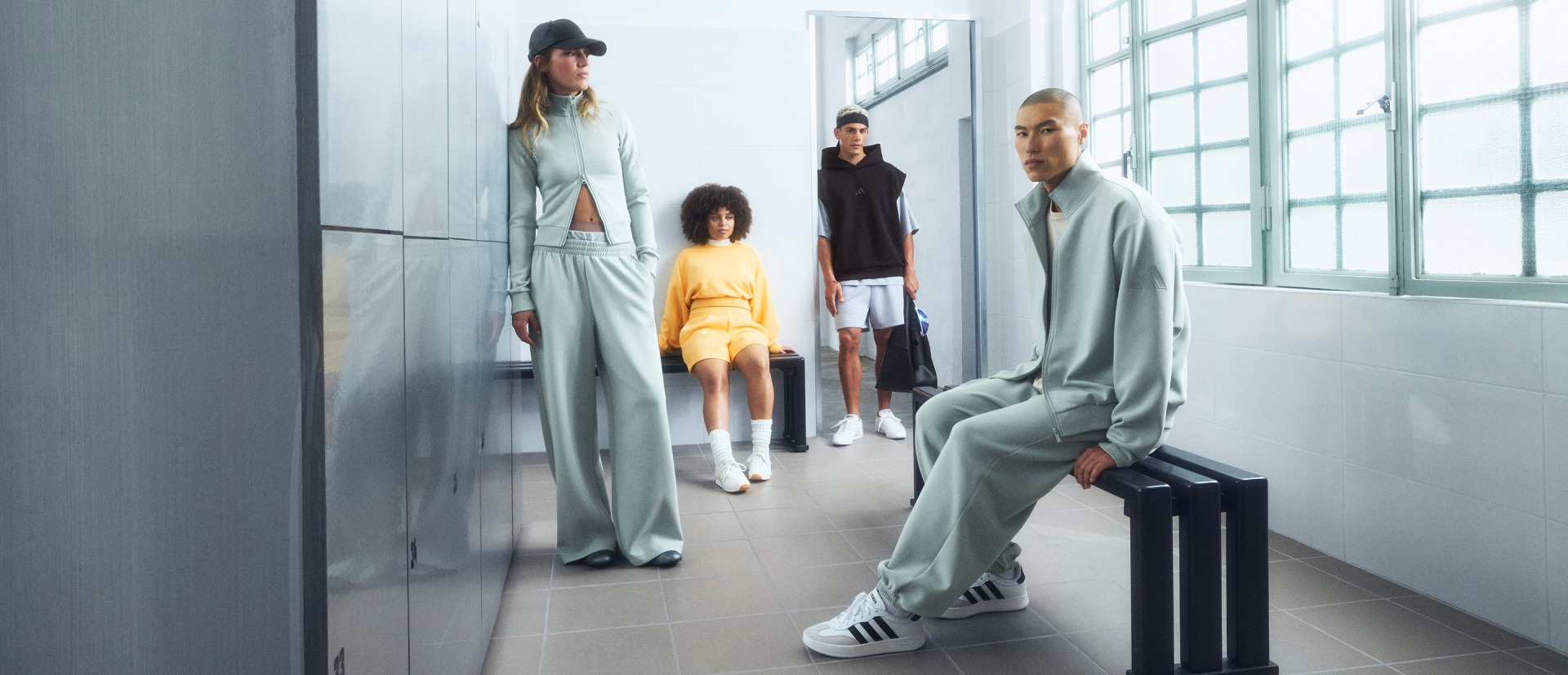 La imagen muestra a un grupo de personas vestidas con ropa moderna y elegante en un entorno interior minimalista y bien iluminado.