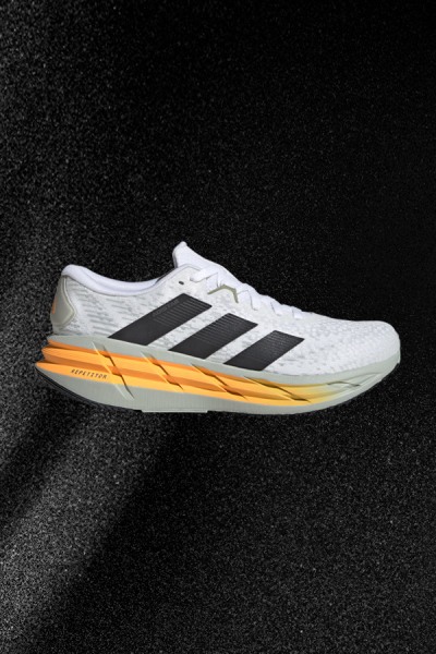 Bielo-oranžové bežecké tenisky adidas na tmavom pozadí.