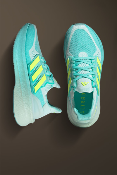 A pair of turquoise and yellow athletic shoes resting on a dark brown surface.