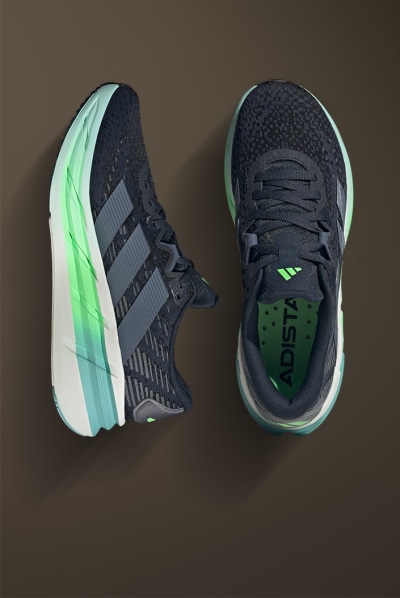 The image shows a pair of black and green athletic shoes with a textured pattern on the upper part and a thick, cushioned sole.