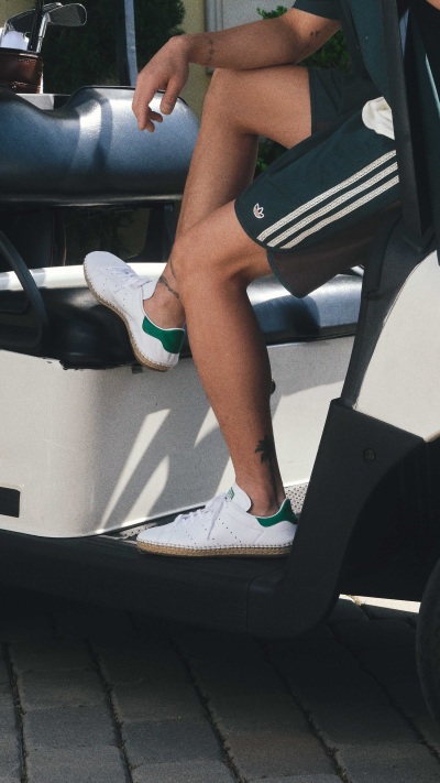 The image shows a person's legs and feet wearing white sneakers and black and white striped socks, sitting in what appears to be a car or vehicle.
