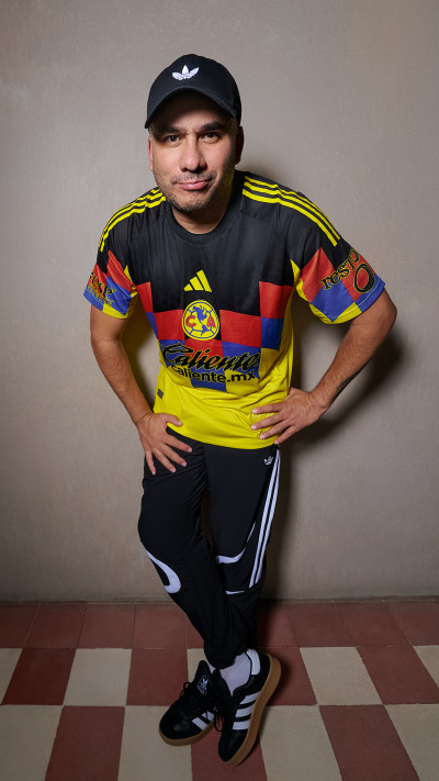 A man wearing a colorful sports jersey and a black cap is standing in a room with a tiled floor.