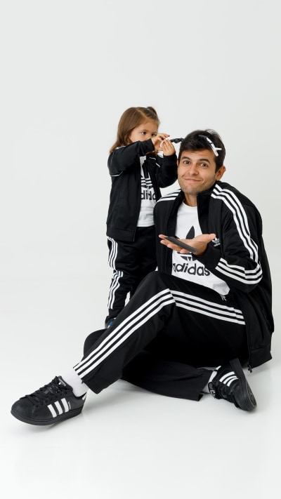 Two individuals, a man and a woman, are sitting together in casual athletic wear against a plain white background.