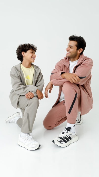Two individuals, a man and a woman, are seated on the floor in casual attire, engaged in conversation or interaction.
