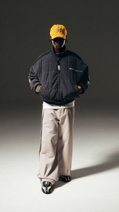 A person wearing a black jacket, yellow helmet, and beige pants stands in a dimly lit environment.