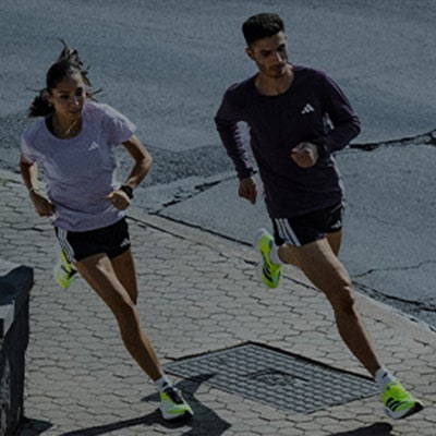 Two people, a man and a woman, are running on a paved path against a backdrop of a dark, cloudy sky.
